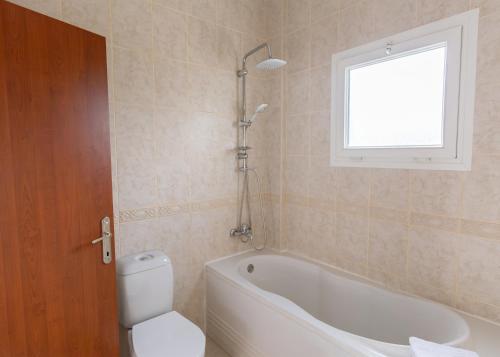 a bathroom with a tub and a toilet and a window at Crystal Villa walk by Merit Casinos By HolidayKeys in Kyrenia