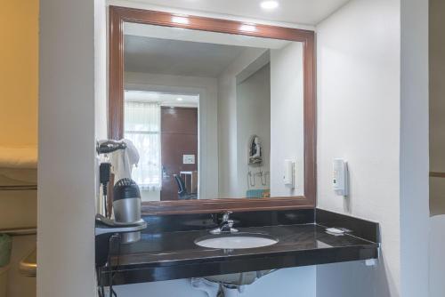 Un baño con lavabo y un espejo grande. en Boca By The Sea Hotel, en Boca Raton