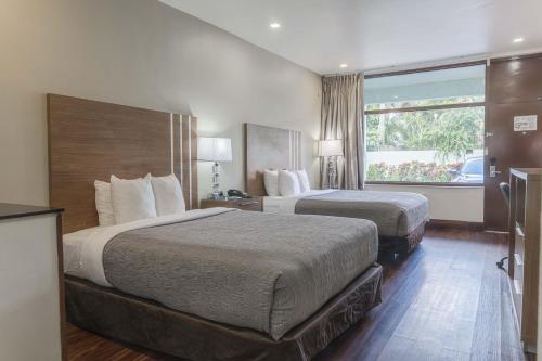 Una habitación de hotel con dos camas y una ventana. en Boca By The Sea Hotel, en Boca Raton