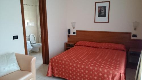 a bedroom with a red bed and a toilet at Hotel Holiday House in San Giovanni Rotondo