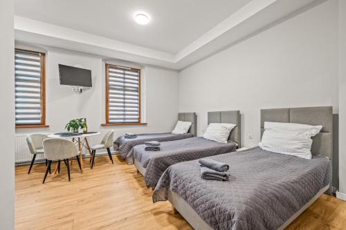 two beds in a room with a table and chairs at Central Platinum Apartments 2 Studio z aneksem kuchennym 3 łóżka in Rybnik