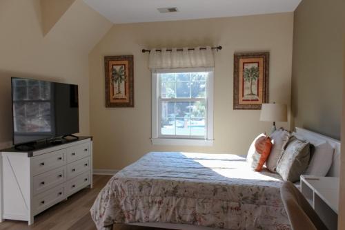 a bedroom with a bed and a tv and a window at Royal Villa in Sunset Beach
