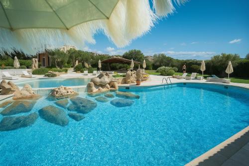 a swimming pool with rocks in a resort at Hotiday Baja Sardinia Saline in Cala Bitta