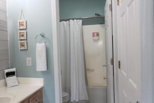 a bathroom with a shower and a white shower curtain at Beach Bungalow by Coastal Concierge in Sunset Beach