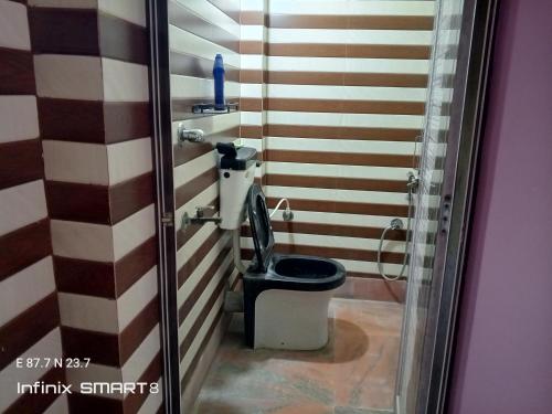 a bathroom with a black toilet in a room at Swpnaneer home stay in Shānti Niketan