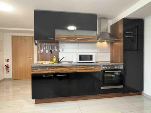 a kitchen with black cabinets and a microwave at STB116 smarte Monteurwohnung in Steinberg