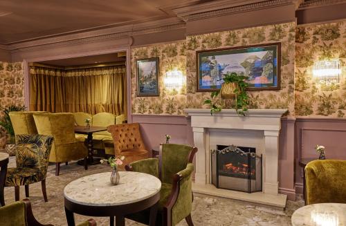 a room with a fireplace and a table and chairs at The Royal Horseguards Hotel, London in London
