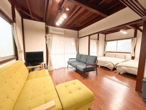 a living room with a couch and a bed and a tv at まるとくハウス霧島 in Kirishima