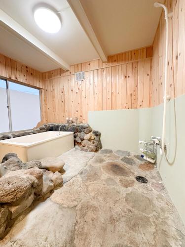 a bathroom with a bath tub and a sink at まるとくハウス霧島 in Kirishima