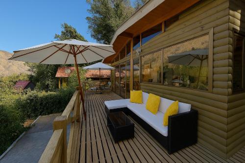 una terraza de madera con un banco y una sombrilla en Carolin Cacao Cabins - Quillay, en San José de Maipo