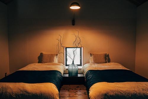 ein Zimmer mit zwei Betten und einer Vase auf einem Tisch in der Unterkunft Ooka Tsuji - tsuji-oooka - - Vacation STAY 01156v in Chikuma