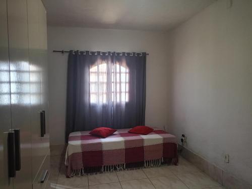 une chambre avec un lit avec des oreillers rouges et une fenêtre dans l'établissement Hospedaria da Gabi, à São Pedro da Aldeia