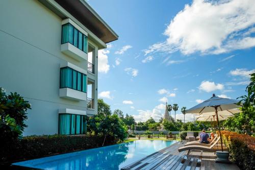 un hombre sentado bajo un paraguas al lado de un edificio en Maraya Hotel & Resort -SHA Plus en Chiang Mai