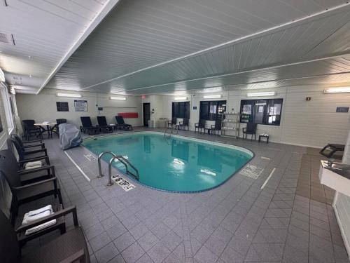 ein großes Schwimmbad in einem Gebäude mit Stühlen und Tischen in der Unterkunft Quality Inn & Suites Green Bay - Ashwaubenon in Green Bay