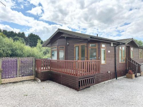 a wooden cabin with a porch and a fence at Kingfisher Cosy Lakeside Lodge in Carnforth