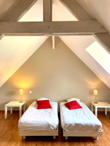 two beds with red pillows in a attic at CÔTE MER in Quiberville