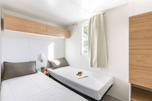 a bedroom with two beds and a window at Eurocamp Mobile Homes at Campsite Valkanela in Funtana