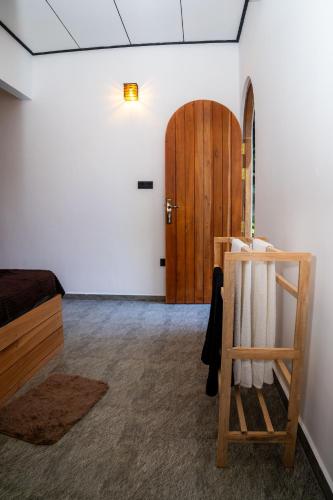 a room with a bed and a wooden door at Ninety Four Plus Madiha in Matara