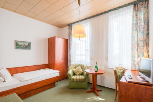 a room with a bed and a desk and a table at Hotel Flora in Bad Harzburg