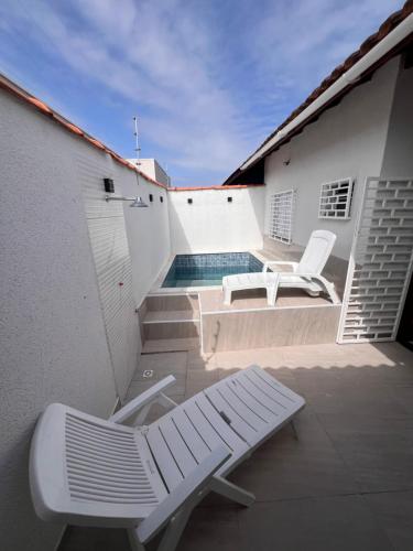 un patio con dos sillas y una piscina en Casa Aconchegante em Itanhaem- Piscina e Churrasqueira 10 pessoas, en Itanhaém