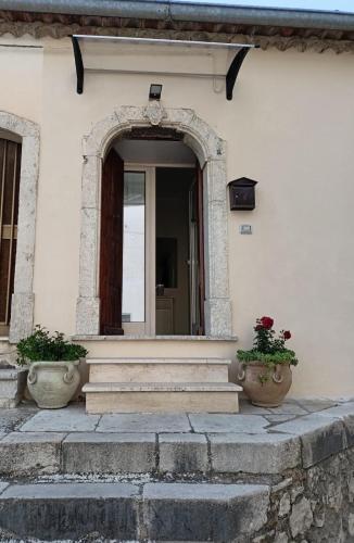 an entrance to a white house with two potted plants at Casa Canale in Gesualdo