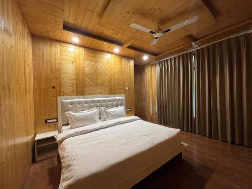 Wood Luxury Hotels Kasauli في كاساولى: غرفة نوم بسرير كبير بسقف