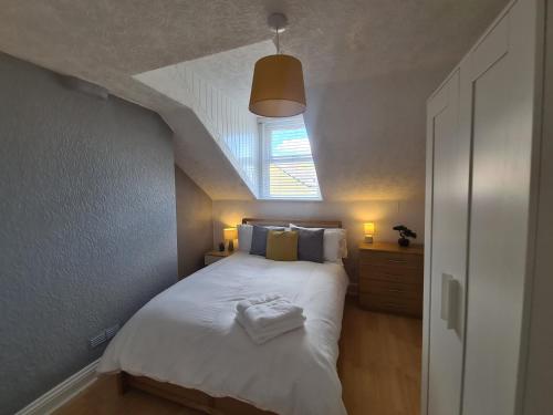 a bedroom with a white bed with a window at 3 Bed - Maisonette - Albert Road in Morecambe