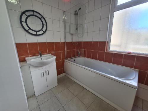 a bathroom with a sink and a bath tub and a mirror at 3 Bed - Maisonette - Albert Road in Morecambe