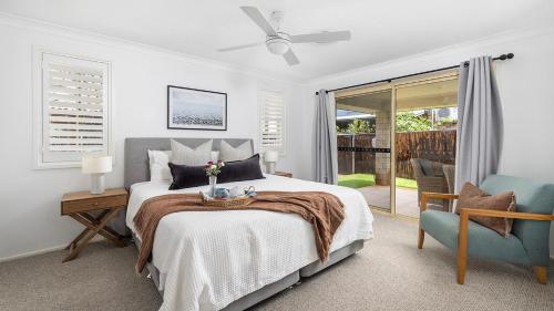 Un dormitorio con una cama y una silla azul. en Salt and Serenity - Lux Home With Heated Pool, en Anna Bay