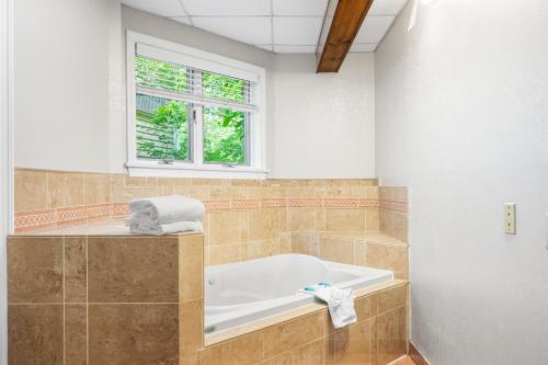 ein Bad mit einer Badewanne und einem Fenster in der Unterkunft Cedar Park Inn in North Stonington