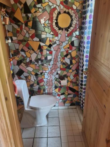 a bathroom with a toilet and a mosaic wall at Hreiðrið cozy cabin in the countryside in Selfoss