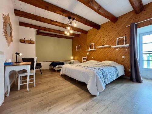 Un dormitorio con una cama y un escritorio en una habitación. en La Maison d'Amélina, en Séneujols