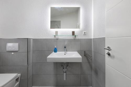 a white bathroom with a sink and a mirror at Motel Ambiente - 4 Zimmer, 2 Bäder in Bad Säckingen