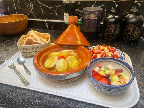 a tray with a bowl of food and a bowl of fruit at Guest house DARNART Hostel in Aourir