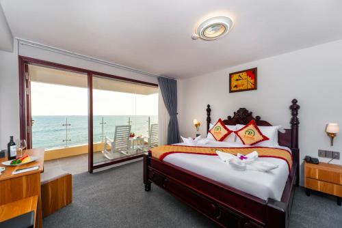 a bedroom with a bed with a view of the ocean at Palado Hotel Mui Ne in Ấp Thiện Phước