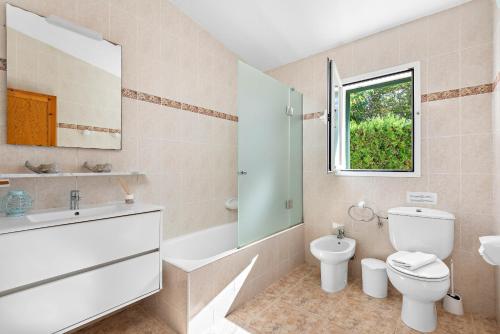 a bathroom with a toilet and a sink and a window at Villa Noelia by Escape Home in Santo Tomás