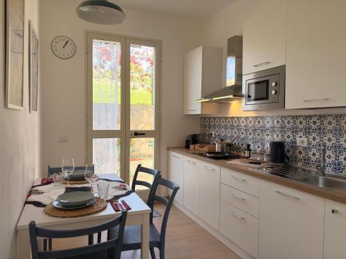 una cucina con tavolo e sedie e una cucina con mobili bianchi di Villa Clara - Comfort e natura nel cuore di Sambuca a Sambuca di Sicilia