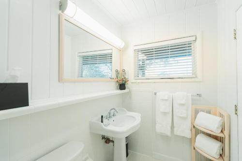 a white bathroom with a sink and a mirror at Pine Needles Lodge in Southern Pines