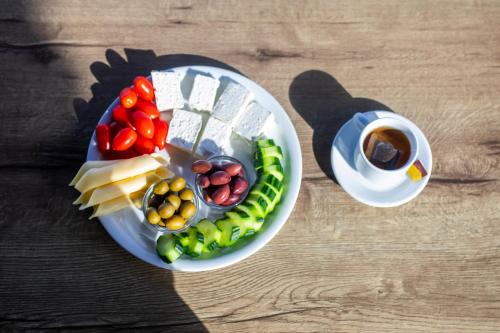 Aeolos Hotel في Kamariotissa: صحن طعام فيه خضار وكوب قهوة