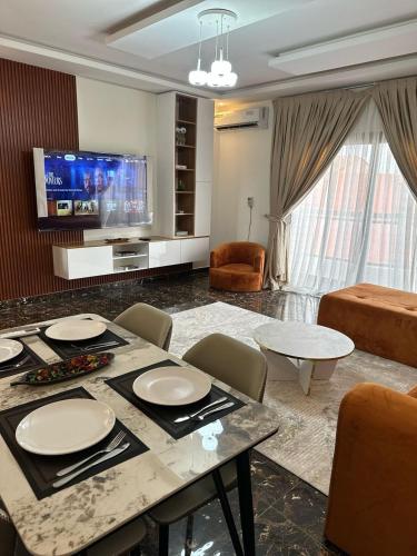 Résidence Diba في داكار: غرفة معيشة مع طاولة مع كراسي وتلفزيون