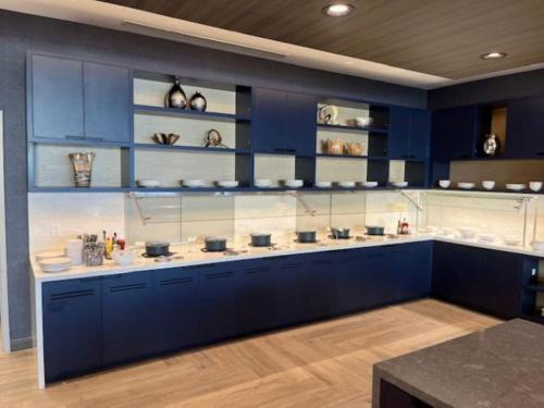 a large kitchen with blue cabinets and shelves at Hyatt Place Toronto Airport in Toronto
