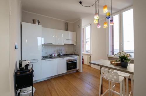 Una cocina con gabinetes blancos y una mesa con sillas. en PrimeLoft Cathedral-Exclusive Suite, en Ferrara