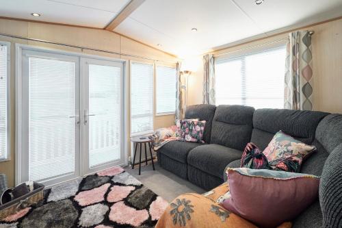 een woonkamer met een grijze bank en ramen bij Host & Stay - Leon's Retreat in Cresswell