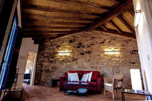 a living room with a red couch and a stone wall at Apartamentos Ribeira Sacra in Parada del Sil