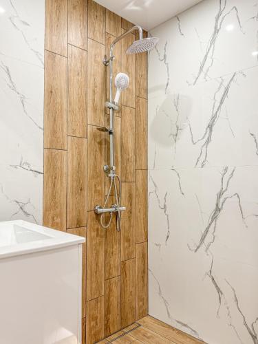a shower in a bathroom with a wooden wall at Skyline Serenity Modern Apartment with Terrace by Flat Manаger in Plovdiv