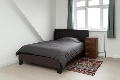 een slaapkamer met een bed, een ladekast en een raam bij Rehoboth Housing in Cranford