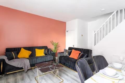 a living room with a black couch with yellow pillows at Mauldeth Shared House in Manchester
