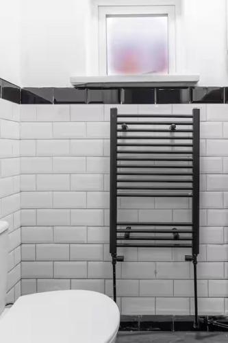 a white tiled bathroom with a toilet and a window at Mauldeth Shared House in Manchester