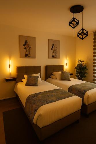 two beds in a hotel room with lights at Elegant Ephesus Suites - Hadrian in Selçuk