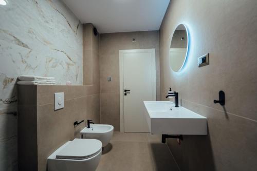 un bagno con due lavandini, un water e uno specchio di SEAPHORIA Luxury Modern Villa a Trogir